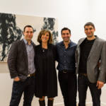 Trois hommes et une femme posent devant un tableau en noir et blanc