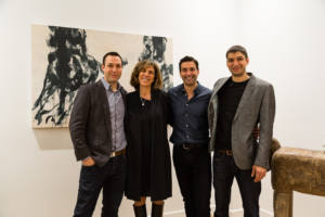 Trois hommes et une femme posent devant un tableau en noir et blanc