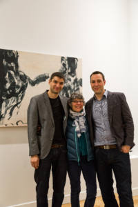 Deux hommes et une femme posent devant un tableau en noir et blanc